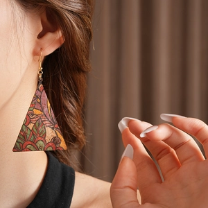 Side view of model wearing triangular vintage print leather earrings with gold hooks