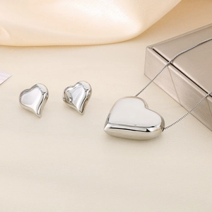 Détail d'un ensemble collier pendentif cœur 3D argenté et boucles d'oreilles assorties