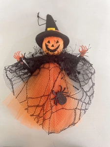 Detail of Halloween pumpkin witch doll featuring orange mesh skirt and black spider web gauze