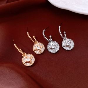 Macro detail of gold and silver plated earrings with starburst zircon round pendants