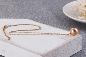 Détail du pendentif perle champagne sur collier doré en titane avec fermoir homard