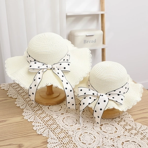 Close-up of woven straw sun hats with scalloped edges and black polka dot ribbon bows