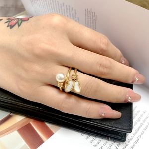 Close-up of golden open ring featuring a white pearl and mother of pearl butterfly charm