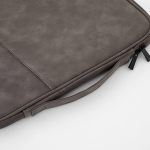 Detail view of smooth dark grey PU leather laptop sleeve with reinforced handle and sturdy zipper