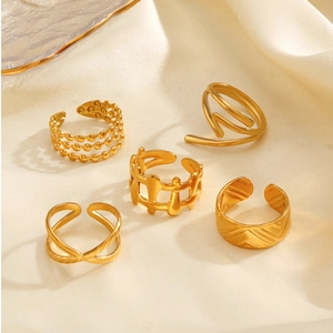 Detailed view of five 18K gold plated stainless steel rings on warm silk fabric