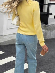 Back view of yellow chunky knit sweater and light blue jeans on an urban street