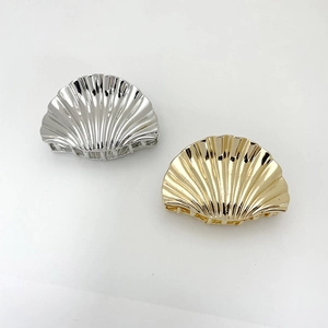 Detail of shell-shaped hair claw clips in polished gold and silver metallic finishes