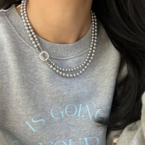 Close-up of double-layer bead necklace featuring a square pendant with gray stone inlay