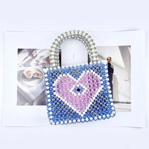 Macro detail of hand-beaded blue bag featuring pink heart and evil eye charm