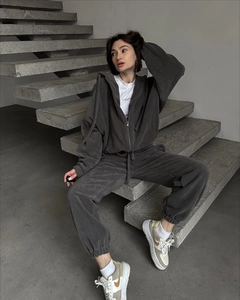 Dettaglio della tuta in pile grigio scuro con cappuccio e pantaloni casual dritti