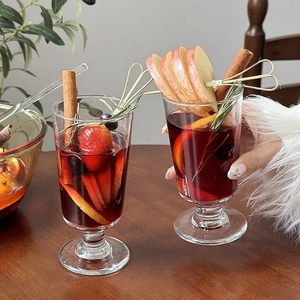 Elegant Christmas mulled wine glasses with fresh fruit garnishes on a rustic wooden table