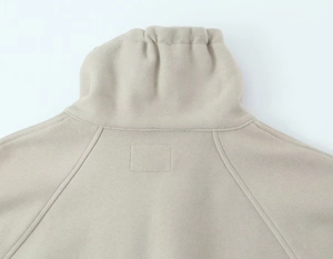 Détail du col montant et de la couture raglan sur ce sweat beige doux à tissu texturé