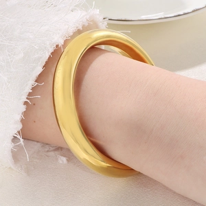 Detailed close-up of 13mm wide 18k gold plated stainless steel chunky bangle on wrist