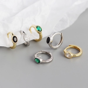 Close-up of minimalist oval zircon hoop earrings in gold and silver finishes