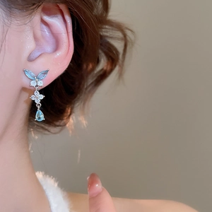 Dettaglio di orecchini a farfalla con ciondolo in zircone blu chiaro indossati
