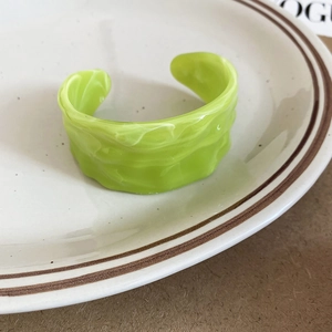 Detail of lime green acrylic cuff bracelet with marble texture and wavy surface