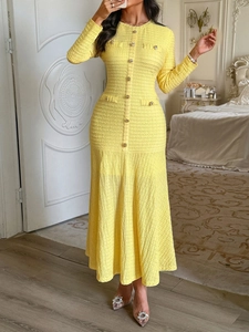 Detail of yellow knit dress featuring decorative metal buttons and tailored waist design