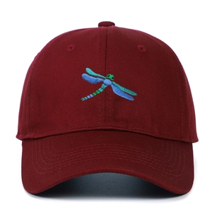 Close-up of a burgundy baseball cap featuring detailed blue and green dragonfly embroidery