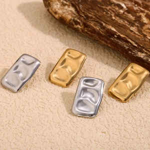 Detail shot of rectangular gold and silver earrings with hammered metal texture