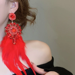 Détail de boucles d'oreilles de luxe à plumes rouges avec strass et motif ethnique