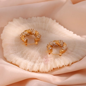 Detail of gold twisted hoop earrings with pave-set zircon on silk and coral decor