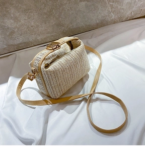 Detail of straw woven texture and metallic gold lock on a minimalist crossbody bag