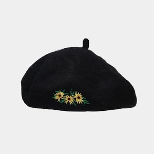 Detail shot of black wool beret featuring three yellow sunflower embroidery accents