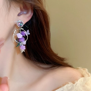 Vue latérale macro de boucles d'oreilles fleur violette avec papillon et gland