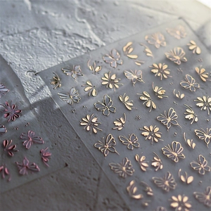 Macro shot of gold and rose gold butterfly nail stickers with metallic line details