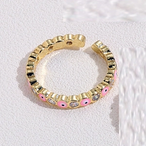 Macro dettagliata di un anello a occhio di Allah dorato con smalto rosa e zirconi