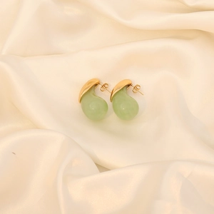 Fashionable light green teardrop stud earrings with gold plating on cream silk background