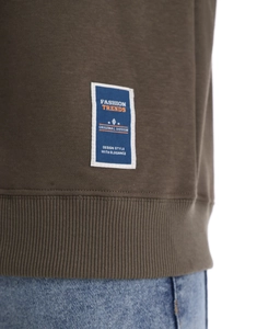 Detailed macro view of olive green cotton sweatshirt hem with blue fashion trend patch