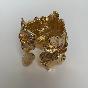 Detailed macro view of the 3D layered metallic flower petals on the gold open cuff bracelet