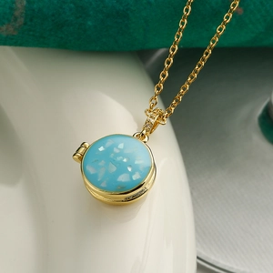Close-up of a gold locket necklace with a blue resin center and shimmering shell inlay
