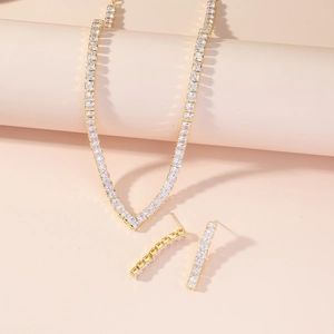 Macro shot of gold V-shaped tennis necklace and long earrings with square cubic zirconia
