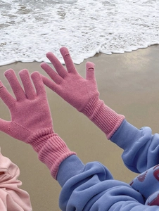 Detalle de la textura de lana de guantes rosas con diseño sin dedos en fondo de playa