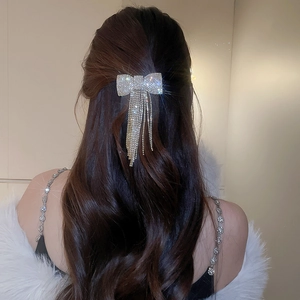 Vue détaillée d'une barrette à nœud strass avec pompons brillants sur cheveux