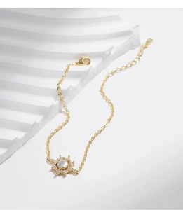 Nahaufnahme eines goldenen Schneeflocken-Armbands mit Zirkonia auf einem weißen Podest