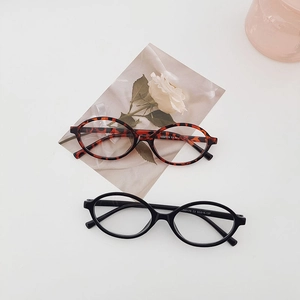 Flat lay of oval tortoiseshell and black sunglasses with slim temples on white surface