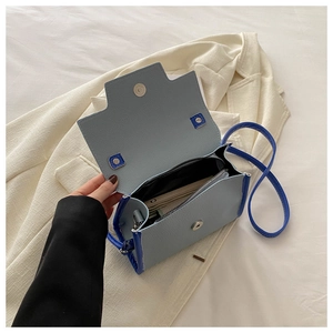 Detail view of small blue crossbody bag showing inner storage for cards and cash