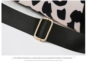 Detail of cow print travel bag featuring adjustable black nylon strap and gold metal buckle