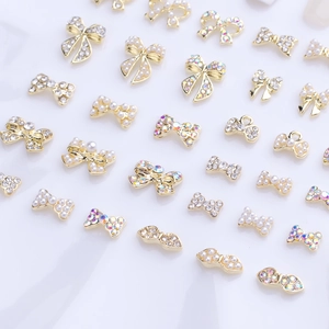Detail of golden bow nail art charms with pearls and rhinestones for 3D manicure decor