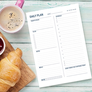 Daily planning notepad with schedule and to-do list on a mint green wooden desk