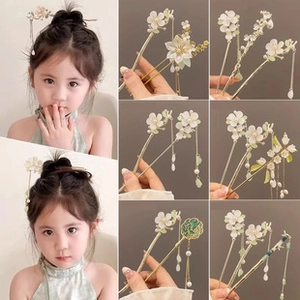 Detailed close-up of white resin flower hairpins with pearls and golden metal tassels