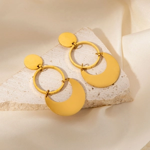 Detailed view of golden geometric earrings with textured stone and fabric background