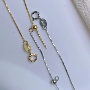 Close-up of S925 sterling silver stamp on gold and silver box chain jewelry clasps