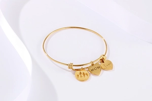Close-up of golden adjustable bracelet with heart charms and MOM engraving for Mother's Day