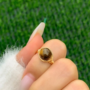 Detailed close-up of handmade gold wire-wrapped ring featuring a brown tiger eye stone