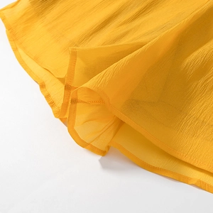 Detailed close-up of yellow ruffled hem with crinkle texture and fine stitching