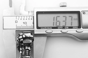 Macro shot showing electronic caliper measuring motorcycle engine pendant size at 16.37mm